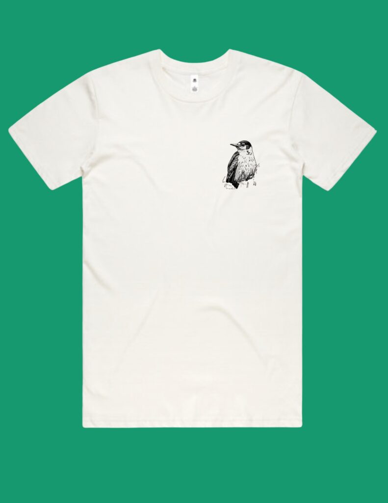 White t-shirt with a small black ink drawing of a bird on the left chest, shown against a green background.