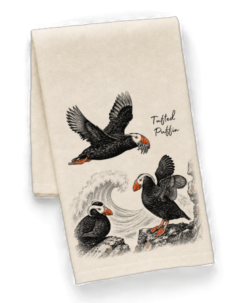 Beige towel featuring a vintage-style illustration of three tufted puffins, one in flight and two perched on rocks with a wave, labeled 'Tufted Puffin'.